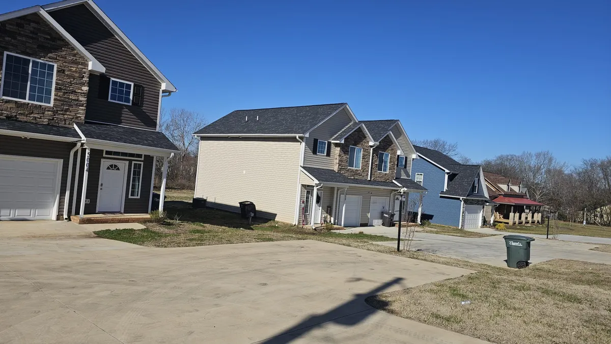 A welcoming exterior shot of modern duplex homes with a paved driveway and lush green grass. The scene suggests a community-friendly environment, with plenty of outdoor space for gatherings, barbecues, or simply relaxing after a day of exploration.